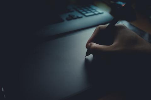 Artistic close-up of a hand extended toward an illuminated wall in low ligh